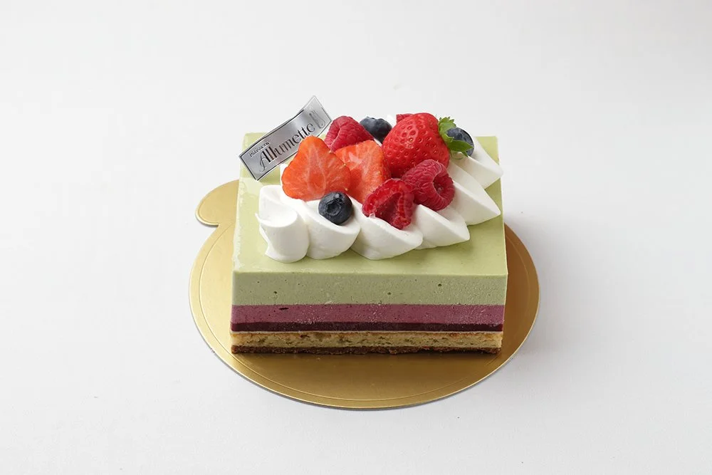 いちご、ラズベリー、ブルーベリーと生クリームを飾った抹茶ムースの四角いデコレーションケーキ